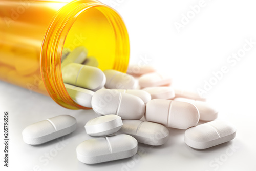 Pills spilling out of pill bottle isolated on white. Medicine and pharmacy concept.