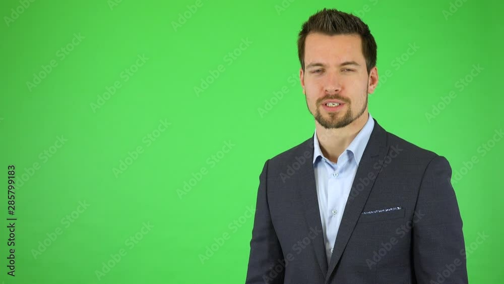 A young handsome businessman talks to the camera and presses invisible buttons in front of him with two fingers - green screen studio A young handsome businessman talks to the camera and presses invisible buttons in front of him with two fingers - green screen studio