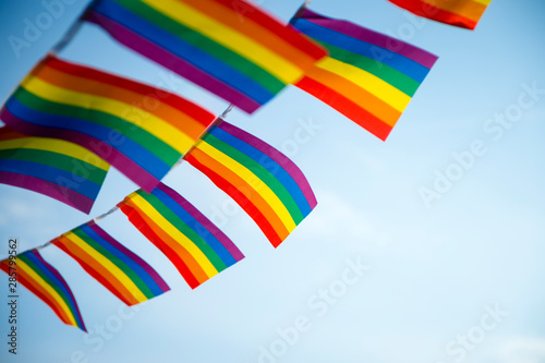 LGBTQI gay pride rainbow flag bunting fluttering in the sky backlit by golden sun