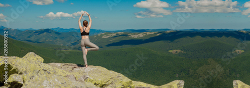 Girl doing yoga exercise lotus pose at the top of the mountain. © volody10