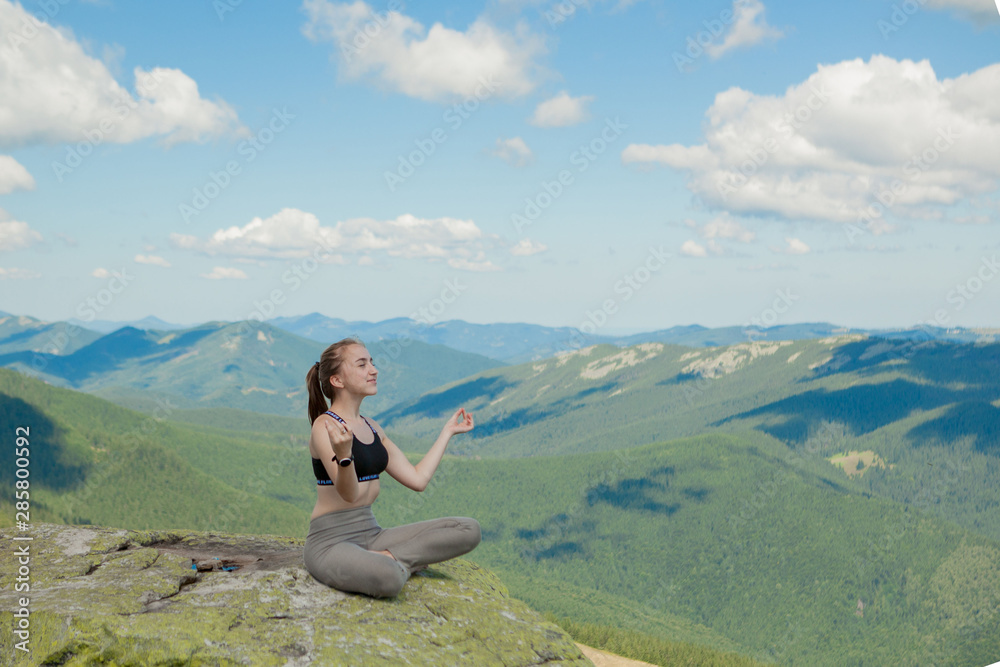 Girl doing yoga exercise lotus pose at the top of the mountain.