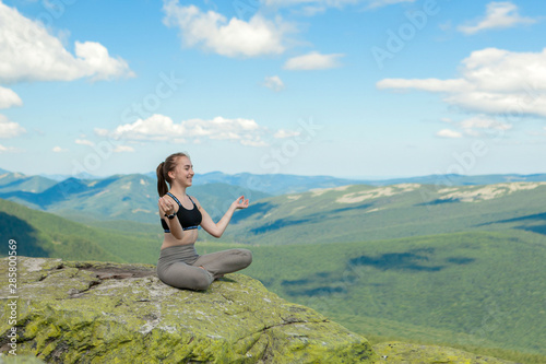 Girl doing yoga exercise lotus pose at the top of the mountain.