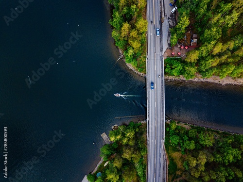 Aerial view of the bridge with a boat passing under it. Blue lake with summer houses in Finland.