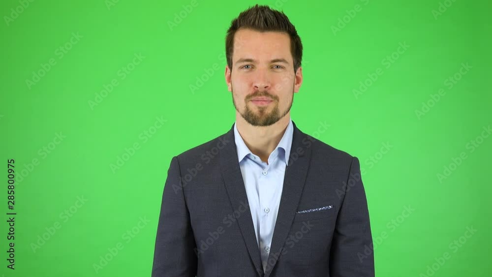 A young handsome businessman talks to the camera and holds a picture in front of him, he enlarges it with his fingers, holds, then lets it go and keeps talking - green screen studio A young handsome businessman talks to the camera and holds a picture in front of him, he enlarges it with his fingers, holds, then lets it go and keeps talking - green screen studio