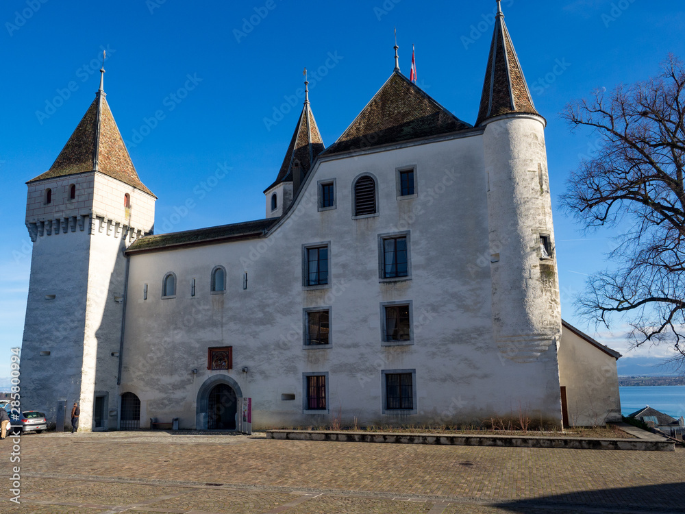 Switzerland, february 2018: Winter day, Castle of Nyon (Chateau de Nyon), Nyon, Switzerland, in a landscape color photo. In this photo you see the castle, garden, buildings and blue sky