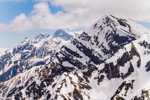 Beautiful panoramic view of Aibga Ridge from the top of the mountain at a height of 2320 meters with huge white clouds casting a shadow. Ski Resort at Caucasus Mountains, Rosa Peak, Sochi, Russia.