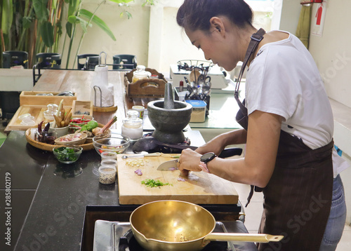 a lady cooking Thai food with brass wok 