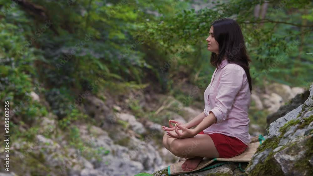 A beautiful girl meditates in a Lotus position, sitting on a mountain. A young woman is engaged in meditation among the mountains and forests. A beautiful girl meditates in a Lotus position, sitting on a mountain. A young woman is engaged in meditation among the mountains and forests.