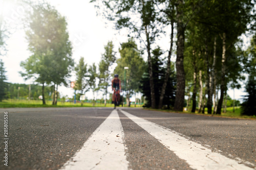 Wallpaper Mural Sportswoman in uniform and helmet riding on the bike path on the background of green trees. Selective focus on the pavement Torontodigital.ca