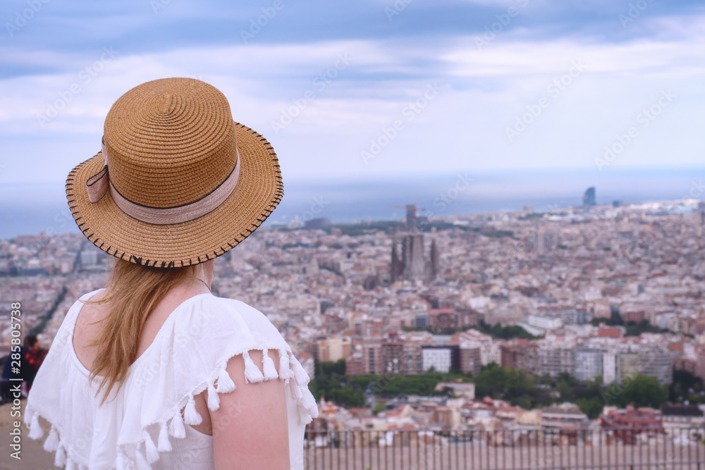 Fototapeta premium Tourist woman in hat looks at the panorama of Barcelona. Catalonia, Spain