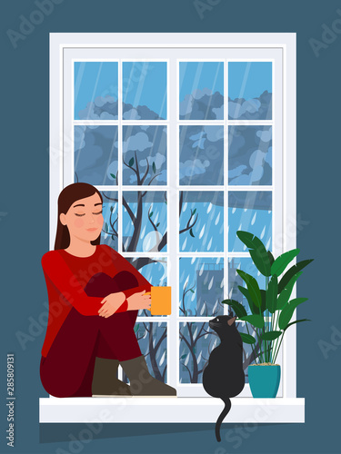 Girl drinks a hot drink while sitting on a windowsill with a cat.