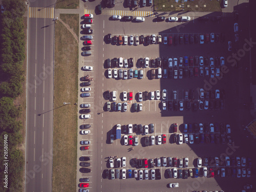 A view from above to the process of car parking. Heavy traffic in the parking lot. Searching for spaces in the busy car park. Parking advice. Cruising for parking in busy business center