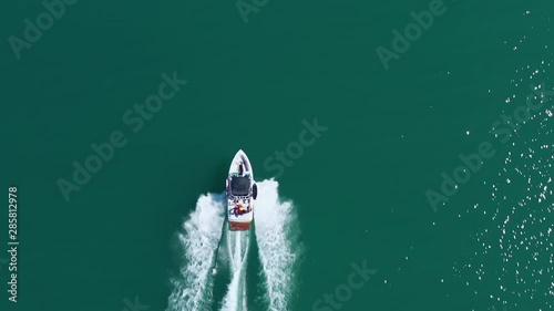 Aerial view, white motor boat on blue sea. Tourists strolling on a boat. White path on water from boat. Recreation.