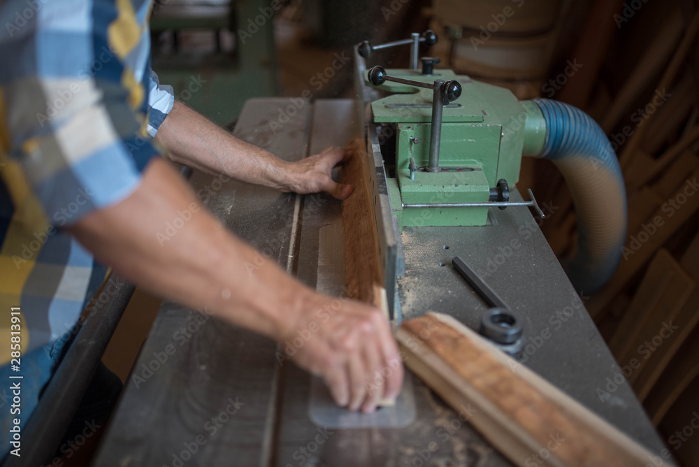 a carpenter processes a massive piece of wood