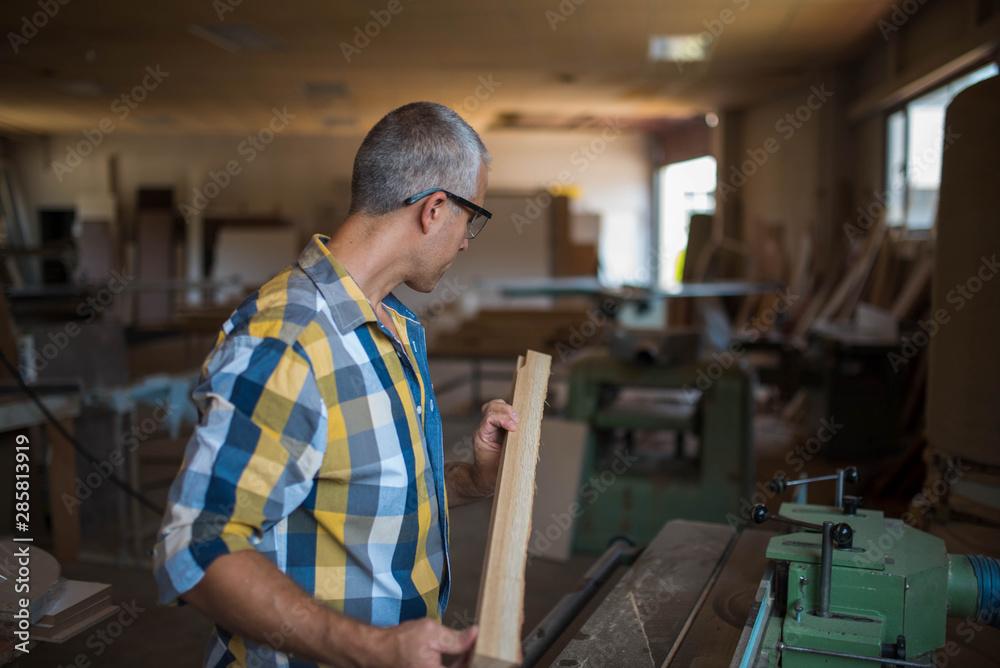 Obraz premium a carpenter measures a massive piece of wood