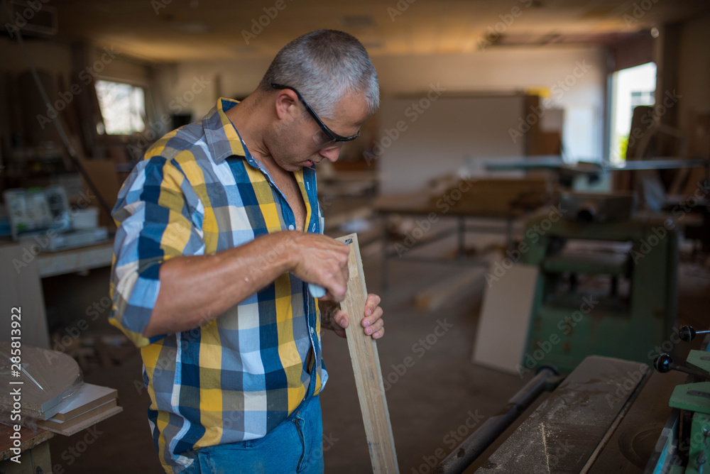 a carpenter measures a massive piece of wood