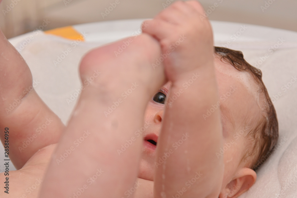 Naklejka premium Pretty three months baby girl taking a bath by her mother at home, european child.