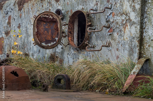 Rusty part of decommissioned marine ship that was cut and left on the shore. photo