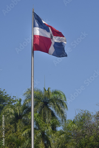 Flag of Dominican Republic (DR) waving in the wind with blue sky on background photo