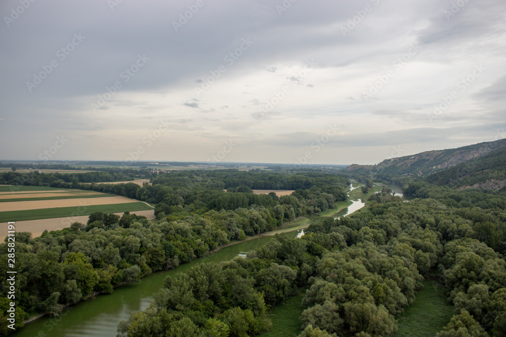 Beautiful natural scenery of river in Slovakia, with a green forest and clouds