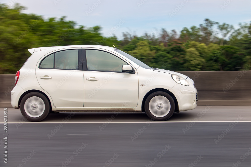 White car rides on highway with background blurred of motion.