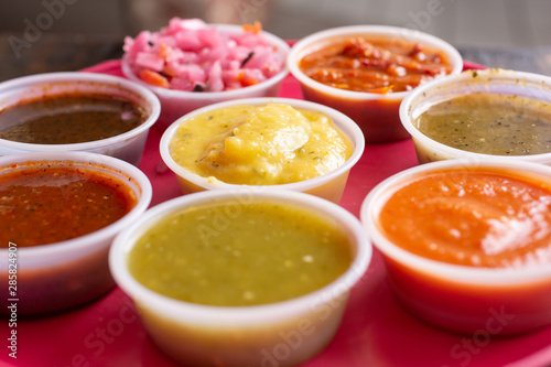 Several Mexican salsas in little cups on a tray