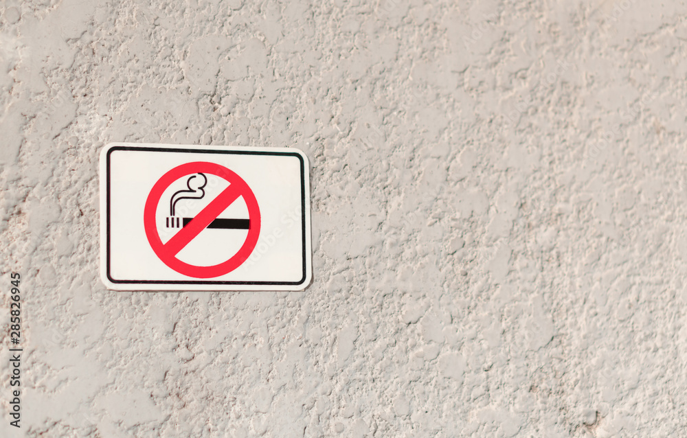 No smoking white sign with cigarette symbol on grunge stone texture wall, smoke strictly prohibited area No smoking white sign with cigarette symbol on grunge stone texture wall, smoke strictly prohibited area