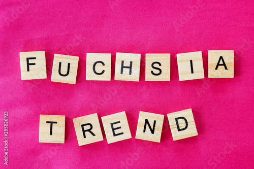 the words fuchsia trend is written in cubic letters on a bright pink color textile background, selective focus