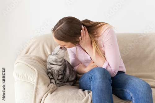 Woman at home kissing her lovely fluffy cat. Gray tabby cute scottish fold cat. Pets and lifestyle concept.