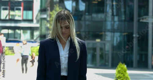 Sad business woman standing outside business building. Unemployment or job problems like  mobbing or harassment concept.