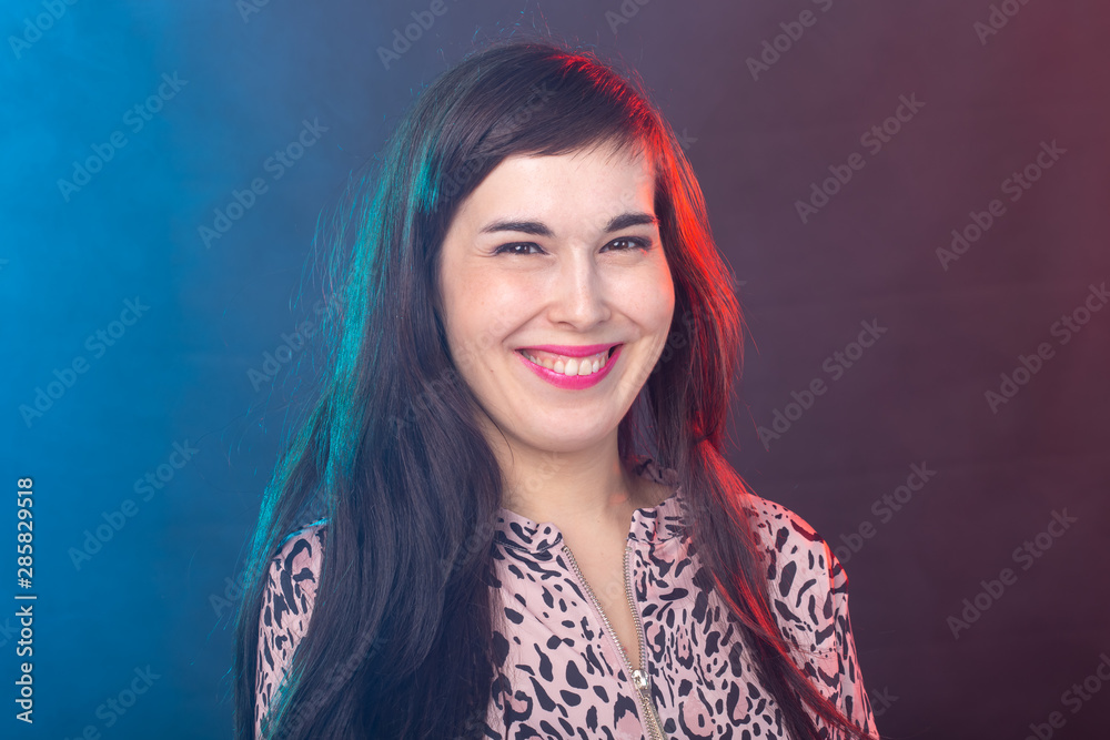 Cheerful funny young brunette woman with long hair posing on colourful background. The concept of a beautiful and well-groomed woman Cheerful funny young brunette woman with long hair posing on colourful background. The concept of a beautiful and well-groomed woman