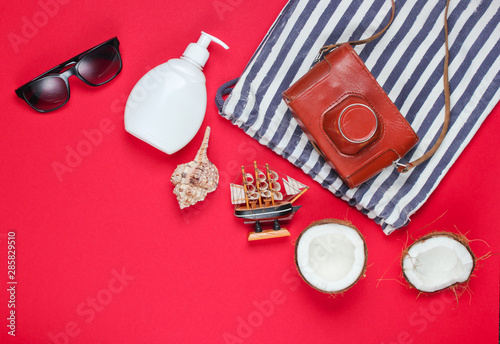 Summer creative background. Beach striped bag, accessories on red background. Top view. Flat lay