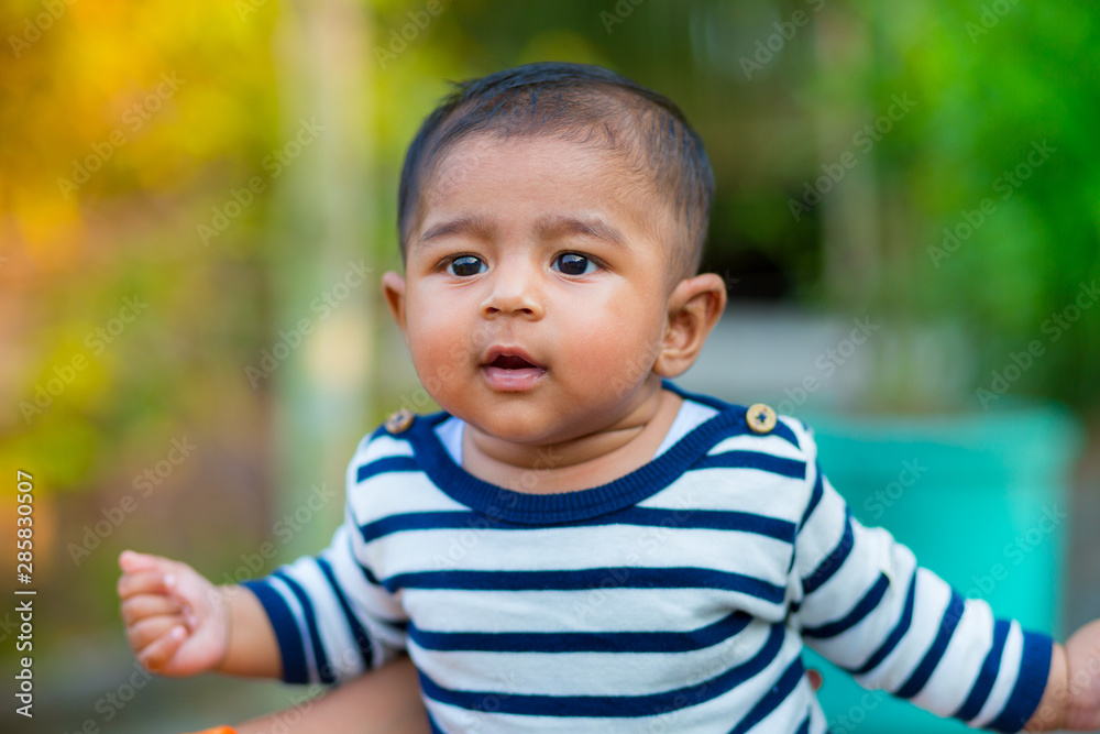 A baby boy looking and smiling. Dressed are white and navy blue striped dress. Baby candid shoot. Baby portrait. A baby boy looking and smiling. Dressed are white and navy blue striped dress. Baby candid shoot. Baby portrait.