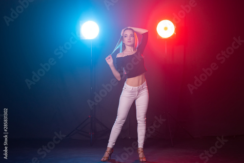 Nightlife and club concept - young woman dancing in the dark under the lights