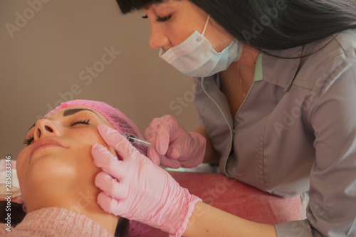 Doctor cosmetologist makes Rejuvenating facial injections procedure for tightening and smoothing wrinkles on face skin of beautiful, young woman in beauty salon.Cosmetology skin care.