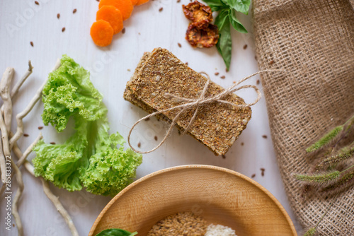 Crispbread tightened by a rope. Healthy food on a white background besid the ingredients in a wooden plate. .Lettuce with carrot near bread cakes