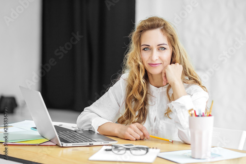 Beautiful woman sits at a desk. Concept for business, work, career.