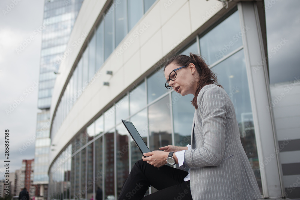 Young ambitious woman with a laptop in her hands on the background of the business center. Young ambitious woman with a laptop in her hands on the background of the business center.