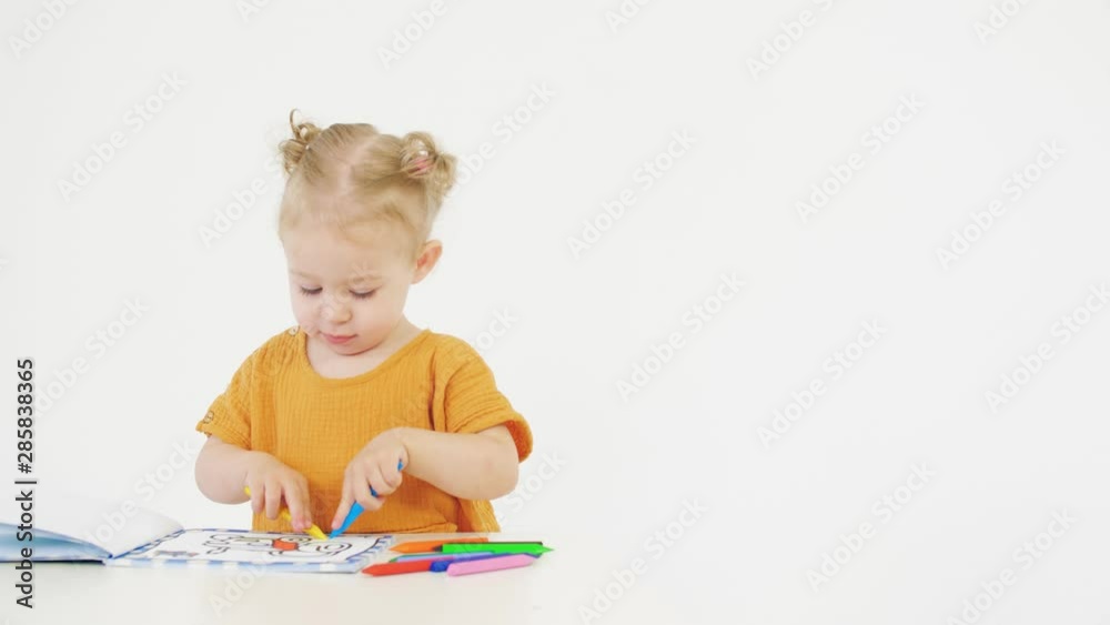 Cute baby girl coloring picture with crayons on white background Cute baby girl coloring picture with crayons on white background