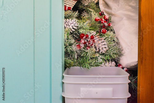Christmas decorations in hawaii packed away for next Christmas, stored inside a closet with a wooden door, next to a vibrant light blue wall.