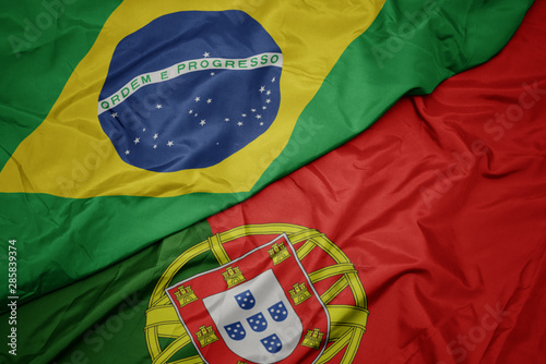 waving colorful flag of portugal and national flag of brazil.