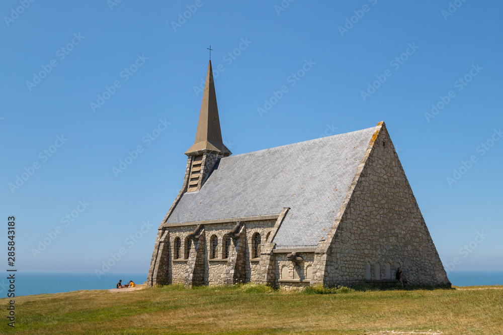 Chapelle Notre Dame de la Garde in Etretat, old medieval catholic Norman church on the hill in a sunny summer day. Etratat, Normandy, France.