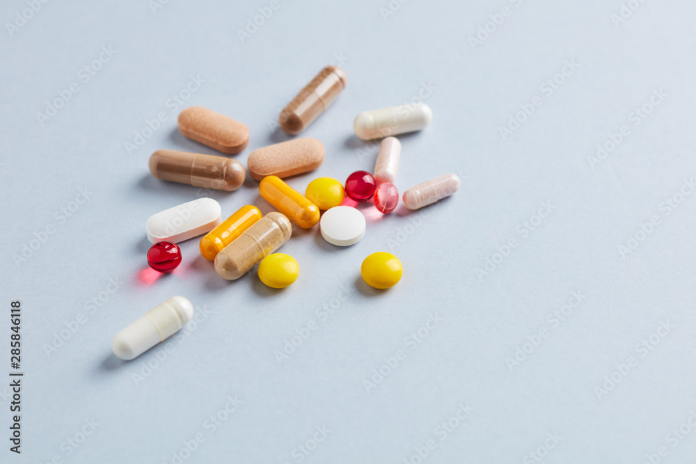 Multicolor vitamins and supplements on bright paper background. Concept for a healthy dietary supplementation. Copy space. Multicolor vitamins and supplements on bright paper background. Concept for a healthy dietary supplementation. Copy space.