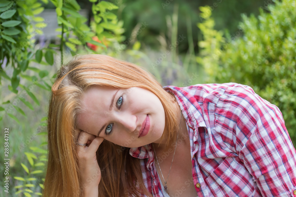 Young woman is dreamily looking at the camera outdoors