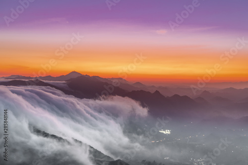 clouds flowing down the mountains like a river at sunset