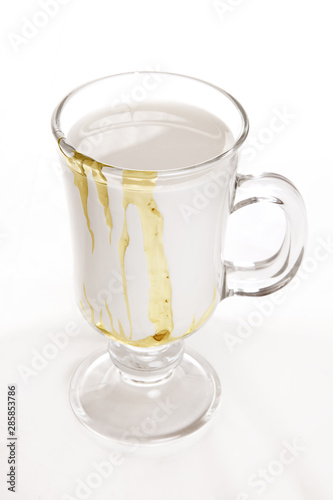 milk with honey in glass on white background