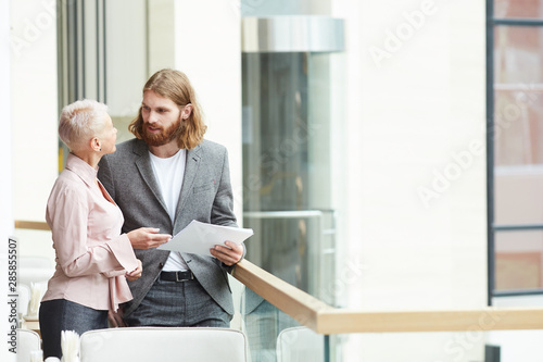 Portrait of two successful business people standing on balcony and discussing work, copy space