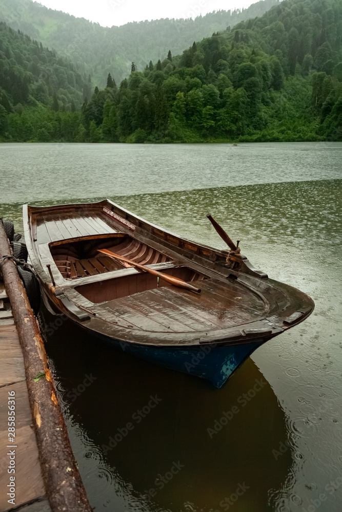 Small fishing boat parked in pond at rainy weather