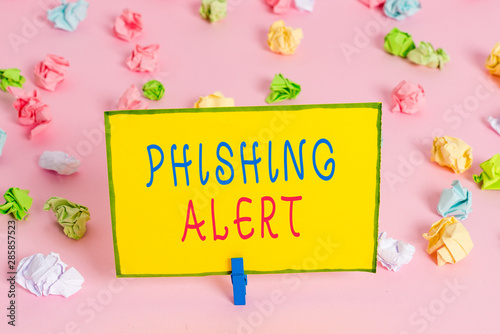 Word writing text Phishing Alert. Business photo showcasing aware to fraudulent attempt to obtain sensitive information Colored crumpled papers empty reminder pink floor background clothespin © Artur