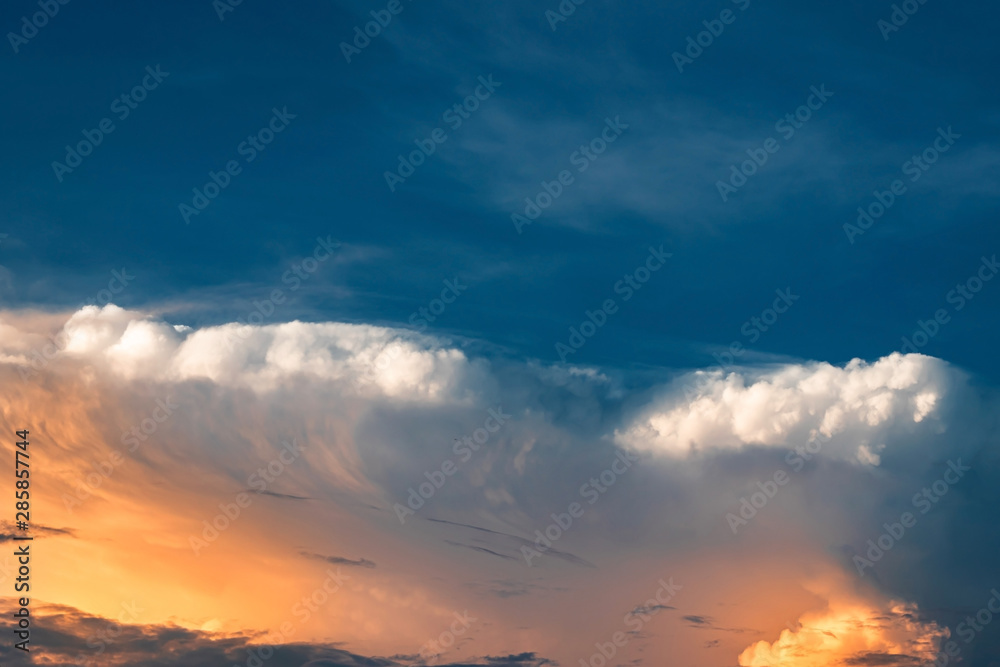Blue sky and cumulonimbus clouds with golden light of sunset. Outdoors beautiful background on summer.